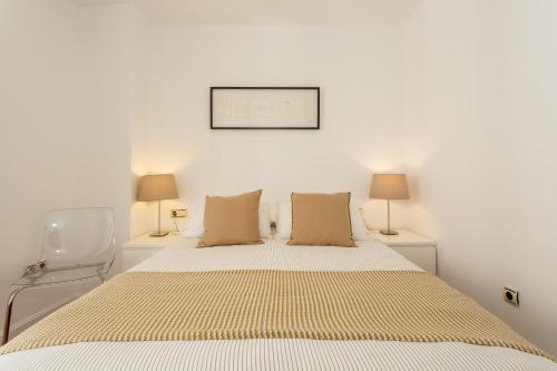 a white bedroom with a large bed with two lamps at Calderón De La Barca in Cádiz
