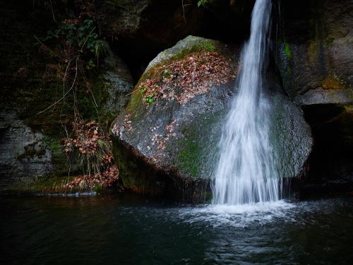 a waterfall on a large rock in the water at U Kosti - Bohemian Switzerland in Děčín