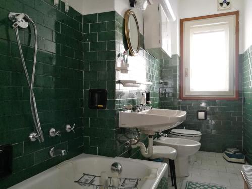 La salle de bains carrelée de couleur verte est pourvue d'un lavabo et d'une baignoire. dans l'établissement L'Atelier du Temps - Appartamento CIRCE, à Courmayeur