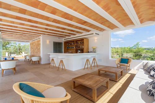 una sala de estar de planta abierta con bar y sillas en Agroturismo Can Toni Xumeu - Adults Only, en Cala Llonga