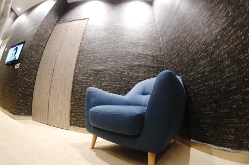 a blue chair in a room with a wall at Here Hotel in Skudai