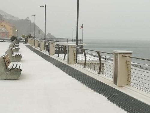 a boardwalk with benches on a beach with the ocean at Come a casa in Deiva Marina