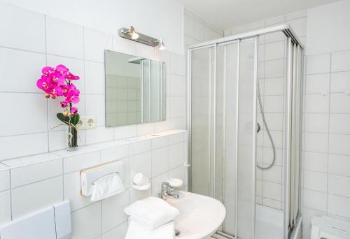uma casa de banho branca com um lavatório e um chuveiro em Hotel Müritzlicht em Waren