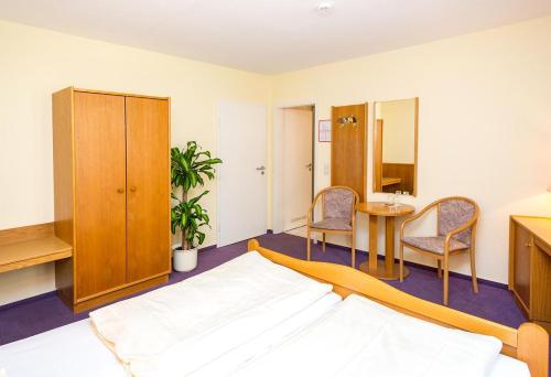 a bedroom with a bed and a table and chairs at Hotel Müritzlicht in Waren