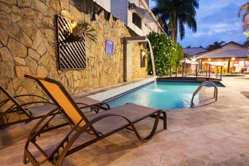 a chair sitting next to a swimming pool at Hotel Ilhas da Grécia in Guarujá