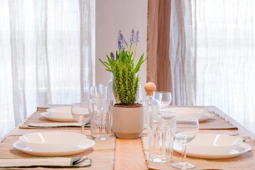 a table with plates and glasses and a potted plant at Maryflower Premium Apartments Piraeus in Piraeus