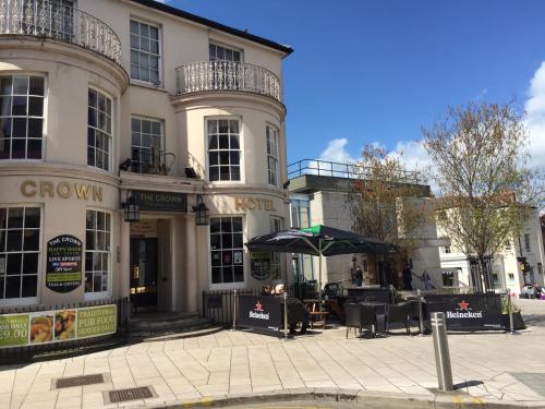 a building with a table and an umbrella in front of it at The Crown Hotel in Ryde