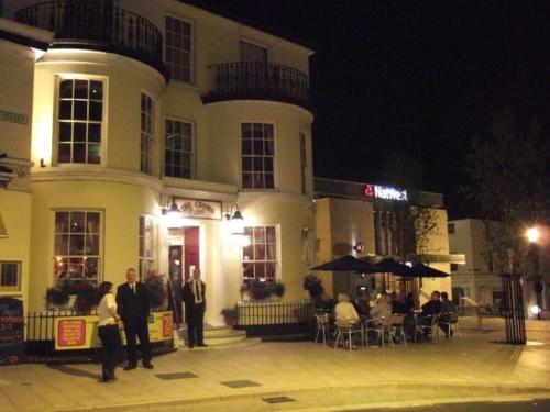 a group of people standing outside of a building at night at The Crown Hotel in Ryde