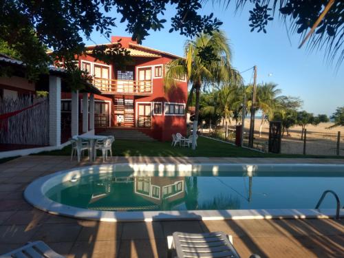 a house with a swimming pool in front of a house at RANCHO GOSTOSO POUSADA in São Miguel do Gostoso