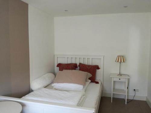 Ein weißes Bett in einem kleinen Zimmer mit einer Lampe in der Unterkunft Haus Friedrichsen in Hollingstedt