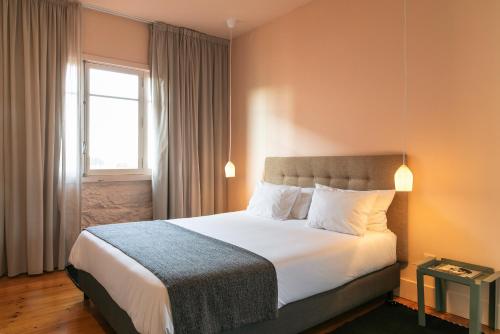 a bedroom with a large white bed with a window at Slowly Garden House in Porto