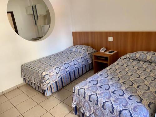 Habitación de hotel con 2 camas y espejo en Hotel Flat Alameda, en Araçatuba