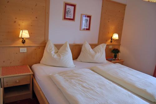 1 dormitorio con 2 camas con sábanas y almohadas blancas en Gasthof Weidmannshof, en Bresanona