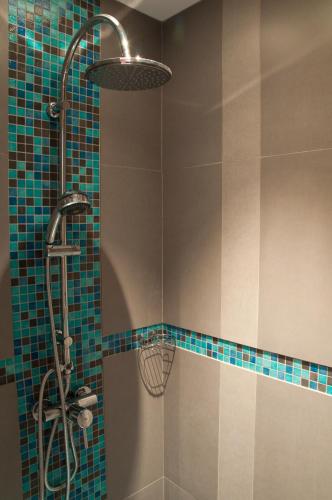 une salle de bain avec douche aux carreaux bleus dans l'établissement Les Jardins de l'Hacienda, à Tarare