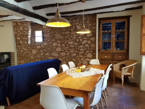 comedor con mesa de madera y sillas blancas en Can Jaume Porxo, en Pratdip