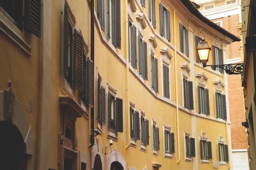 a yellow building with shuttered windows on a street at Hosianum Palace in Rome