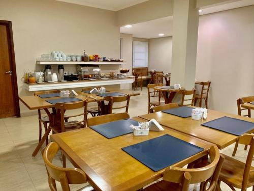 uma sala de jantar com mesas e cadeiras de madeira em Hotel Flat Alameda em Araçatuba