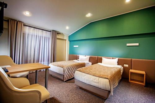 a hotel room with two beds and a green wall at Lumarc Hotel in Bishkek