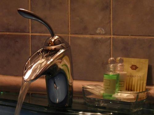 a sink with a faucet and a bottle of soap at Dvůr Olšiny -Hotel and Horse-riding in Karviná