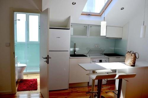 una cucina con armadi bianchi, tavolo e lavandino di Arts, Cultural & Design District with a Sunny View a Lisbona