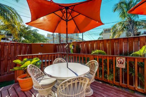 a table and chairs with an umbrella on a deck at Hummingbird Home Suites in San Pedro