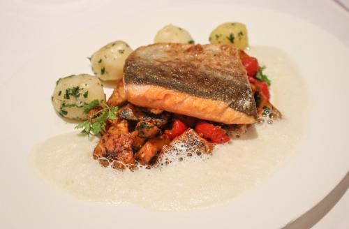 a plate of food with a piece of fish and vegetables at Relais & Châteaux Bülow Palais in Dresden