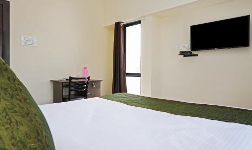 a bedroom with a bed with a flat screen tv on the wall at Treebo Lotus Baner in Pune