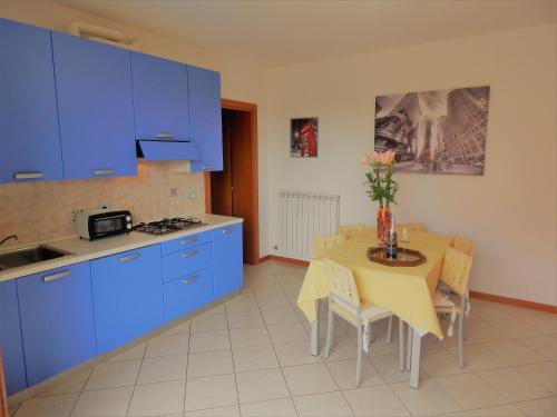 a kitchen with blue cabinets and a table with chairs at RESORT VILLAGE AQUA MARINA FAMILY - Daily Rooms Tidying - CocktailsBar- Pet Friendly - with Hypermarket - Delivery Restaurant-Pizzeria - Room Breakfast with supplement - Ultra Fast Wi-Fi - Play Area for children - Olympic Swimming Pool - Parking in Caorle
