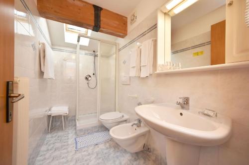 a white bathroom with a sink and a toilet at Villa Gemmy in Pozza di Fassa