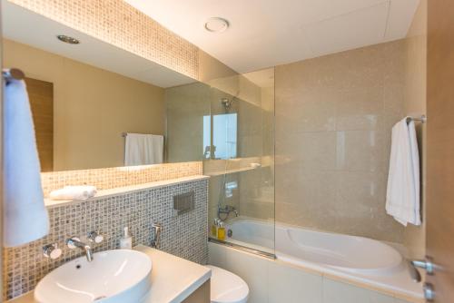 a bathroom with a sink and a tub and a mirror at bnbmehomes - Elegant & Stylish Studio in Downtown - 502 in Dubai