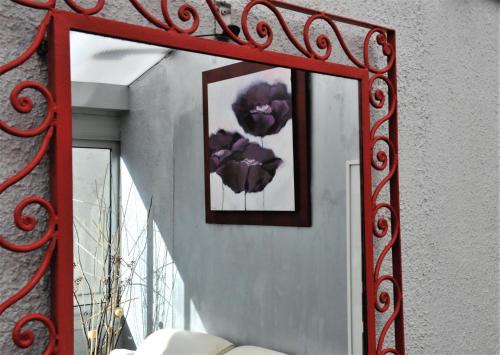 a mirror with a red frame on a wall with flowers at Hôtel Saint Jean in Tours