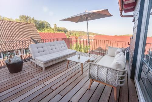 a patio with a couch and an umbrella on a deck at Hotel Restaurant Der Engel, Sasbachwalden in Sasbachwalden