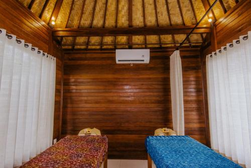 a room with two beds and a wooden wall at Lembongan Small Heaven Bungalow in Nusa Lembongan