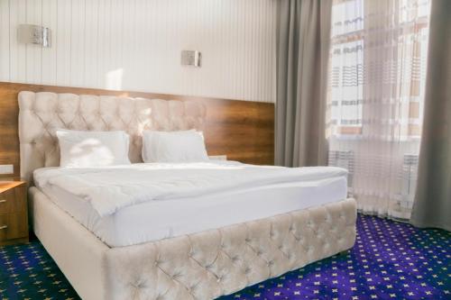 1 cama blanca grande en una habitación con ventana en Hotel Khanaka en Türkistan