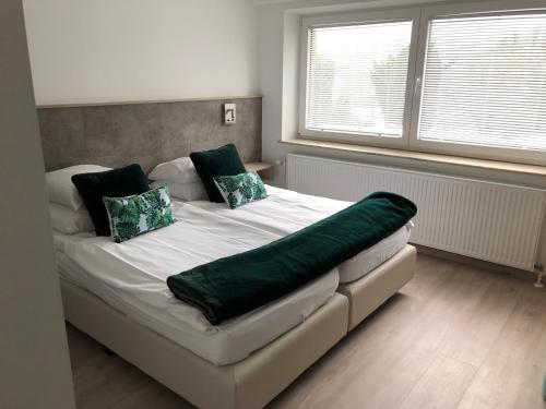 a bedroom with a large bed with green pillows at Hotel Hotleu in Waimes