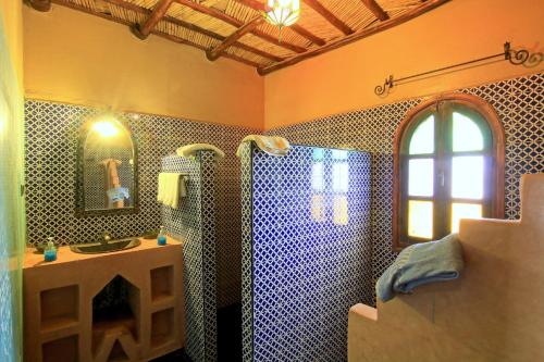 a bathroom with a shower and a sink and a mirror at Dar Tafouyte in Merzouga