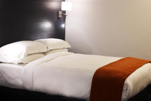 a bedroom with a bed with white sheets and pillows at ONOMO Hotel Waterfront in Cape Town