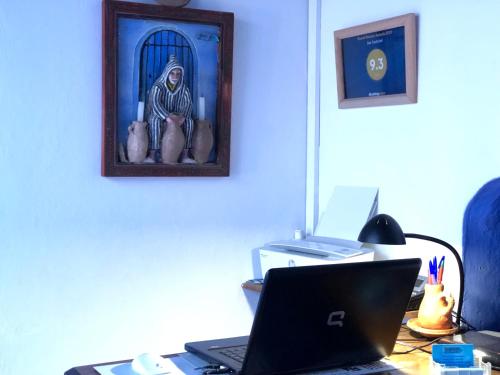a desk with a laptop computer and a picture of a religion at Dar Dadicilef in Chefchaouen