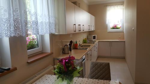 a kitchen with white cabinets and a vase of flowers at LAZUR in Gąski