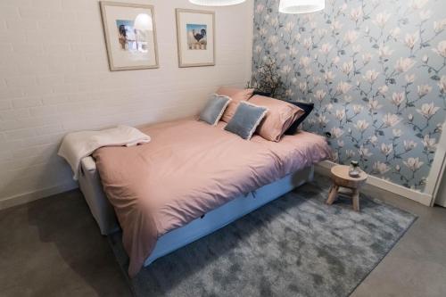 a small bed in a room with pink and blue wallpaper at Blauwe Lucht in Deurne