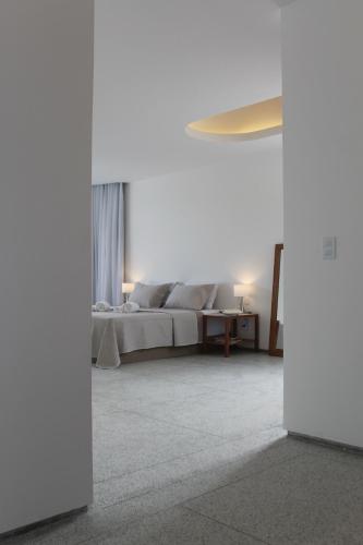 a white bedroom with a bed and a table at Orlanova Boutique Hotel in Arraial do Cabo