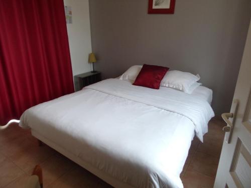 a bedroom with a white bed with a red pillow at Domaine de Bel Air in Cérans-Foulletourte