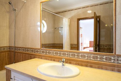 Un baño con lavabo y un espejo grande. en Apartamentos Benvindo by Umbral, en Albufeira