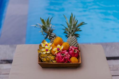 a basket of fruit on a table next to a pool at Lembongan Small Heaven Bungalow in Nusa Lembongan