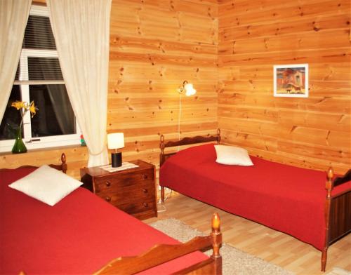 two beds in a room with wooden walls at Silfvastas Holiday Homes in Lapinjärvi