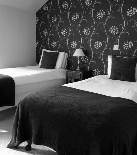 a bedroom with two beds and a black and white wallpaper at the noel @ whitwell in Oakham