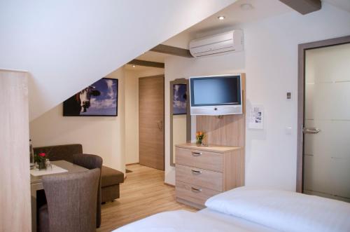 a hotel room with a bed and a tv at Gasthof Ziegler Hotel & Restaurant in Lindau