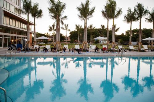 a swimming pool with chairs and palm trees in front of a building at Legacy Hotel at IMG Academy in Bradenton