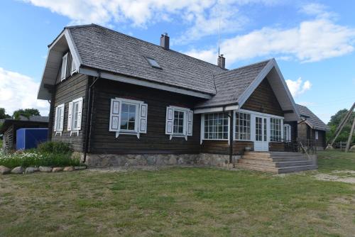 a wooden house with white windows on a yard at Labanoro troba in Labanoras
