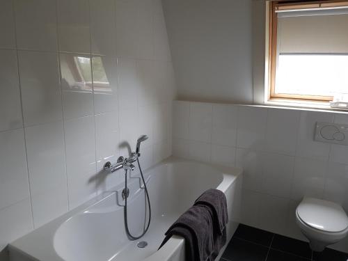 baño blanco con bañera y aseo en B&B de Remketting, en Slijk-Ewijk